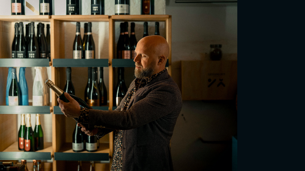 Weinberatung im WeinHaus: eine Flasche entdecken, umgeben von Weinregalen.
